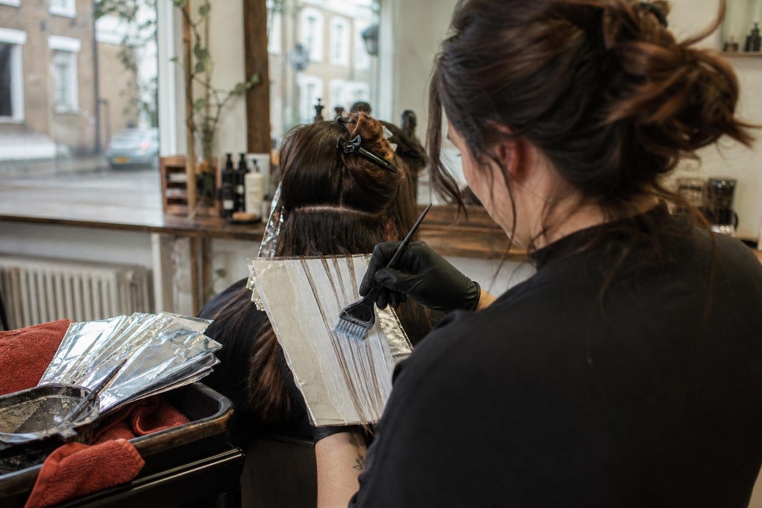 A colourist painting balayage through foils in a small salon, the work a Google Ads budget is meant to fill