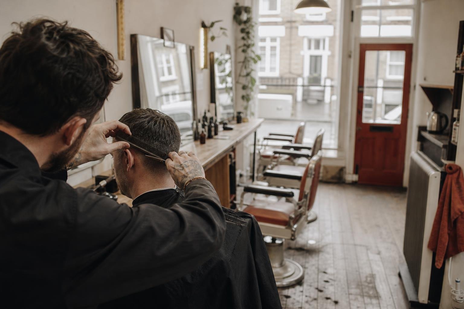 A barber combing through a client's hair in the kind of small independent shop that runs Google Ads with no website