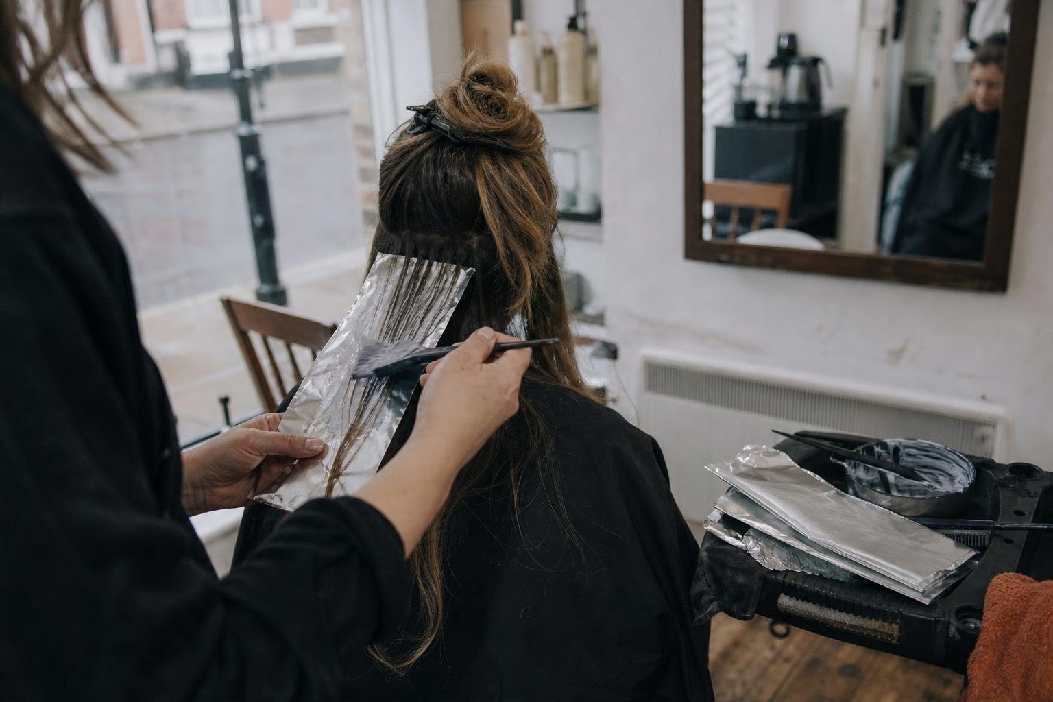 A stylist painting balayage into a client's hair, the work Instagram shows off and Google Ads gets searched for