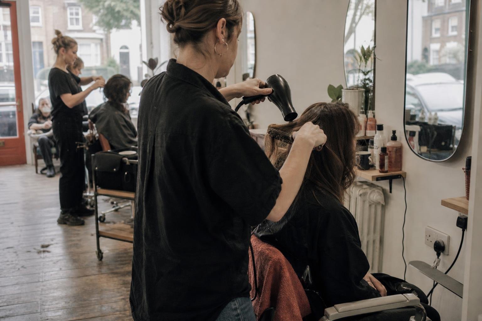 A stylist blow-drying a client at her own rented chair in the kind of shared salon Google Ads has to work in