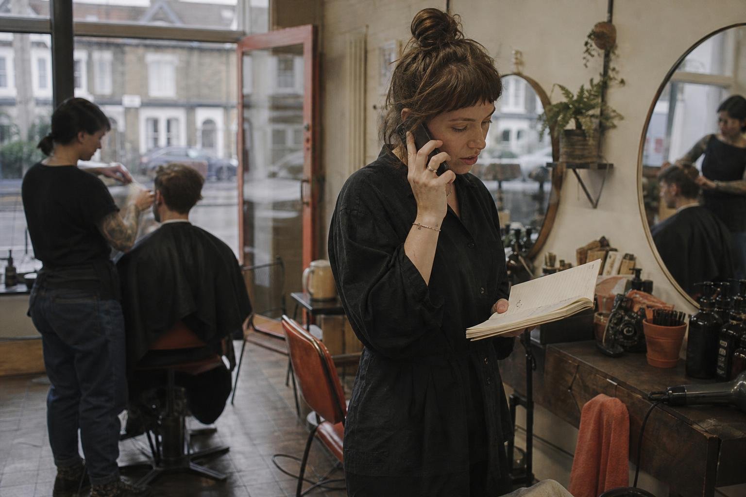 A chair renter taking a booking call with her diary open, the call a Google Ads click is meant to produce