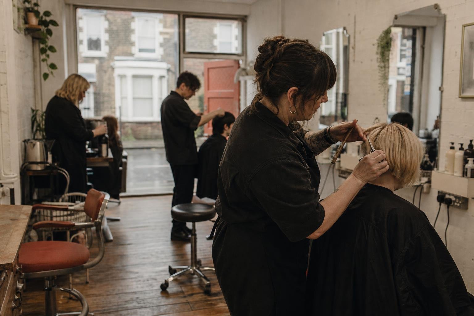 A stylist at her own rented chair with colleagues working behind her, the setting for a Google listing when you rent a chair