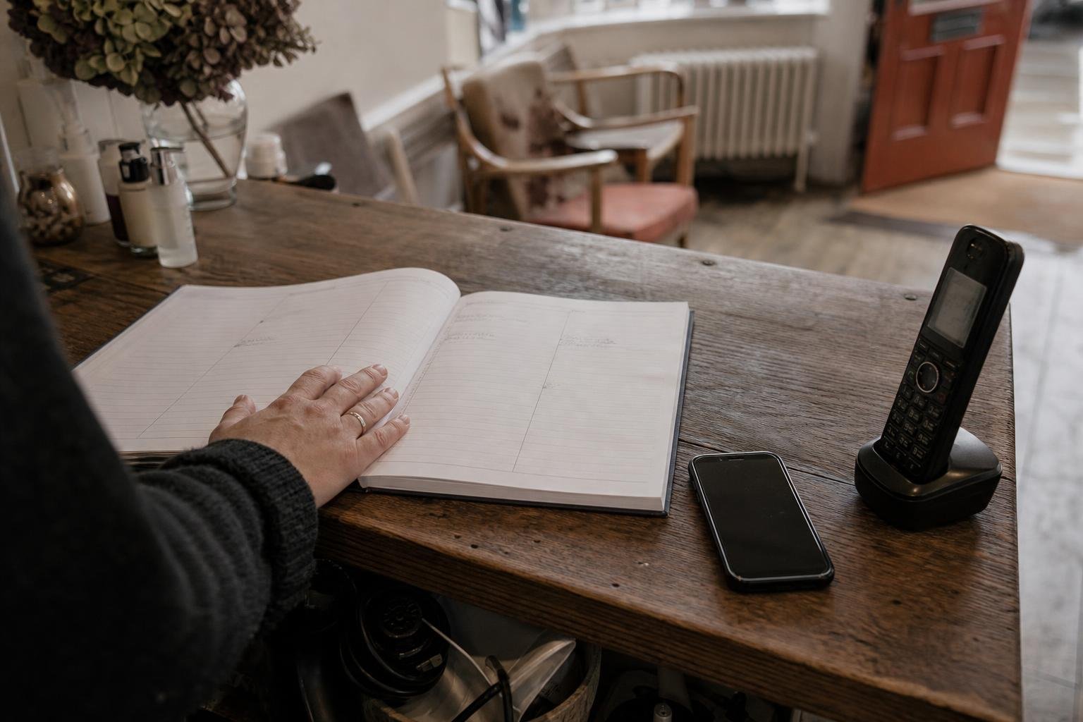 A hand on an open appointment book with a mostly empty week, waiting for salon Google Ads to start working