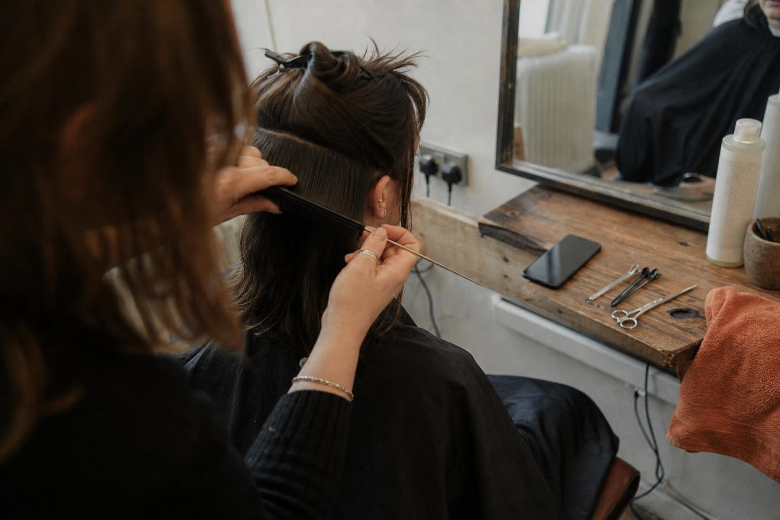 A stylist sectioning a client's hair with her phone face down beside her, getting salon clients without Instagram
