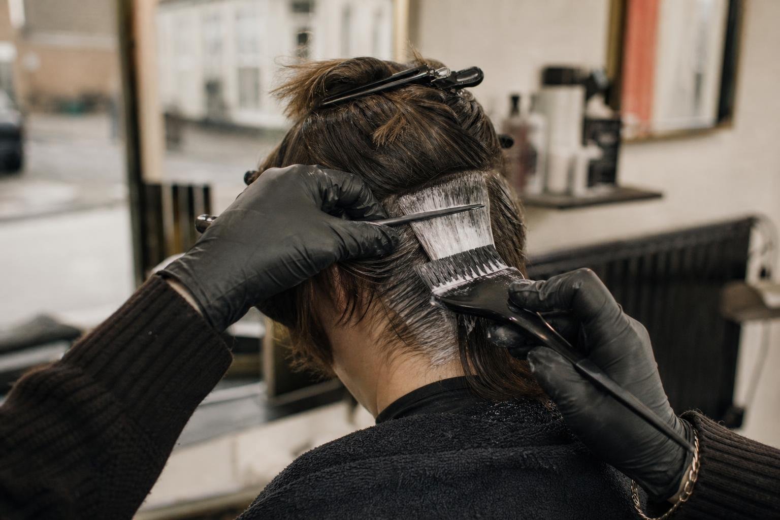 A stylist's gloved hands painting colour, the two hours of chair time a Groupon deal for a salon has to cover