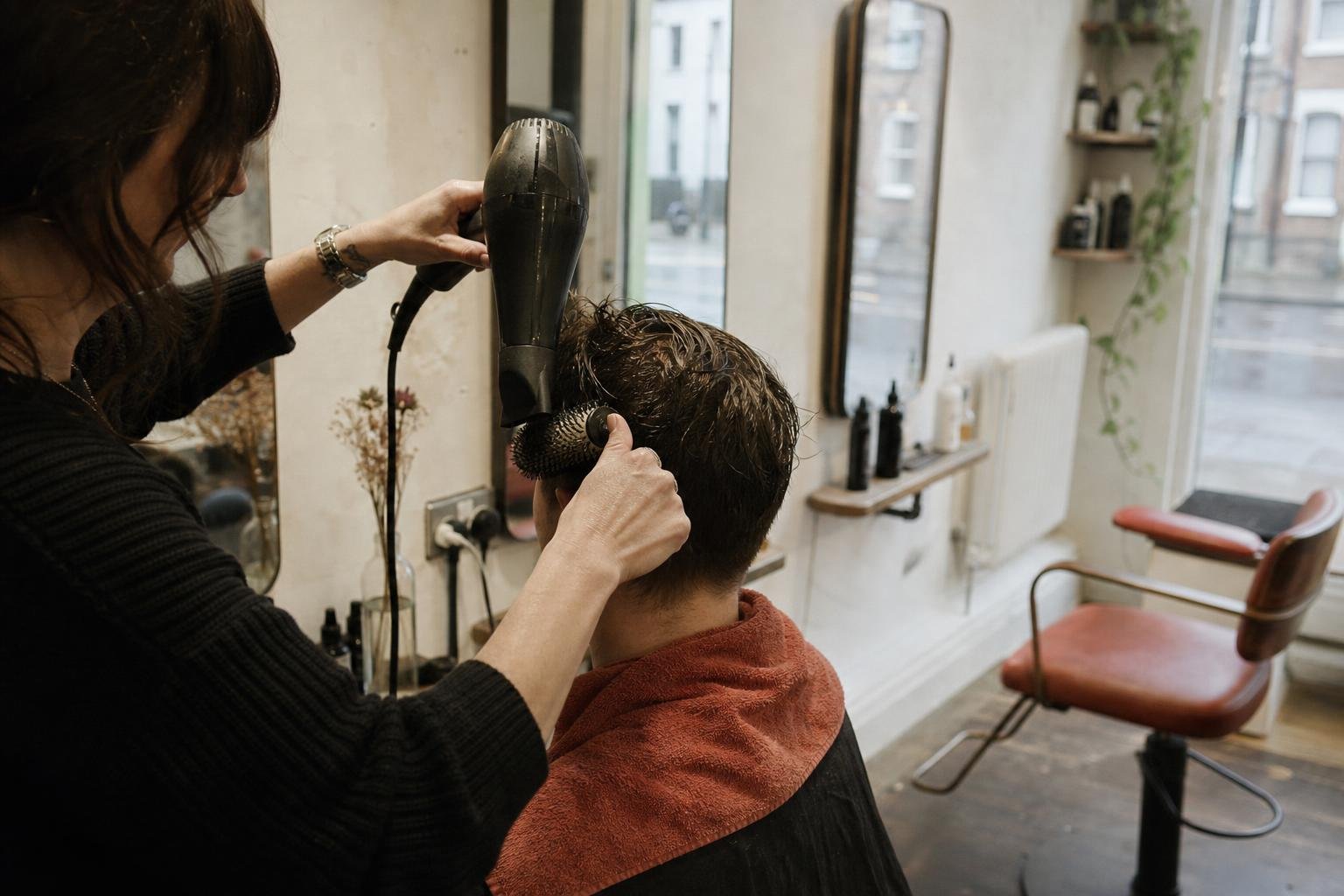 A stylist blow-drying at a shared salon chair, where a chair renter's own Google Maps listing gets complicated