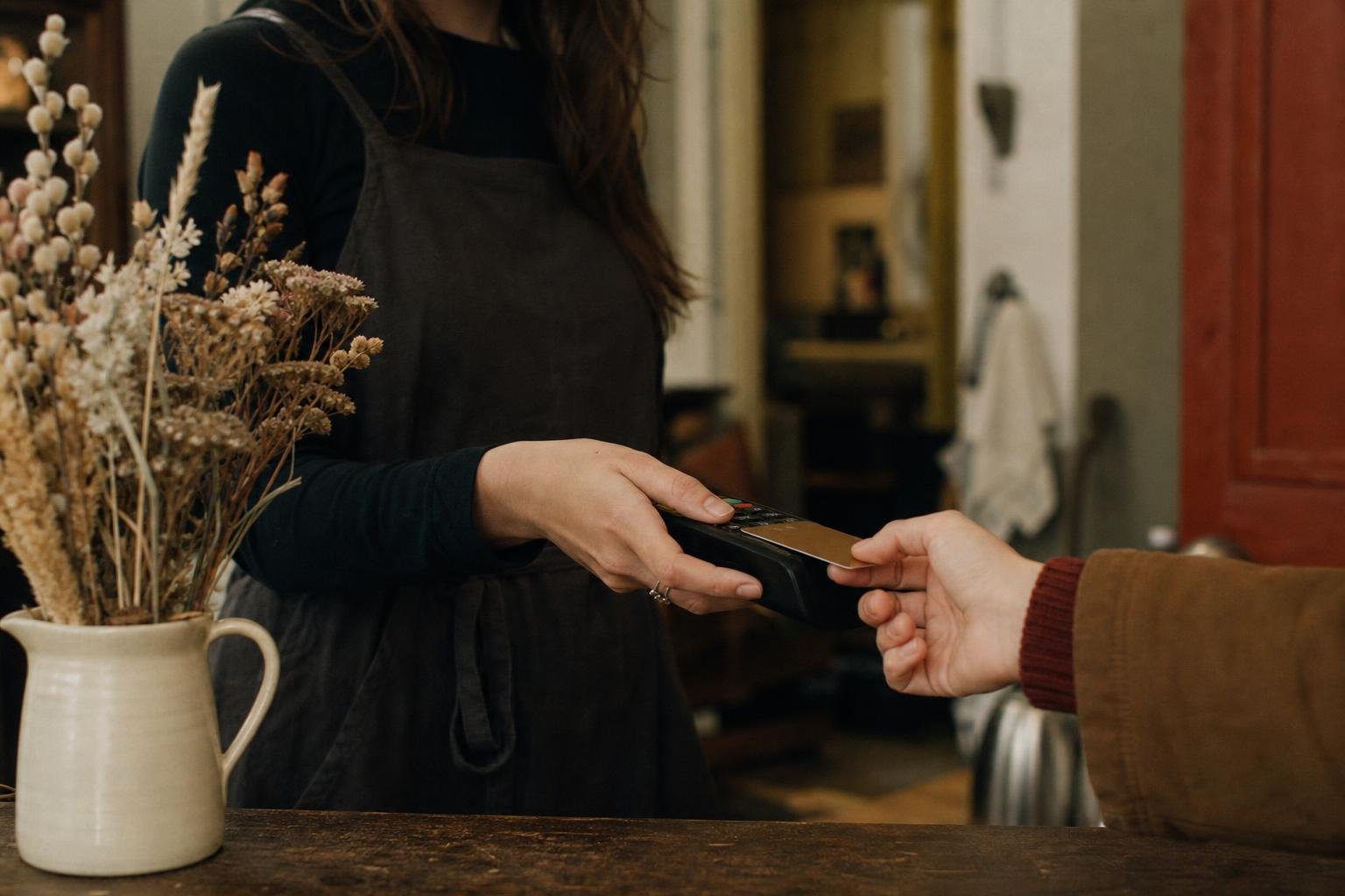 Two pairs of hands and a card machine across a small salon reception counter