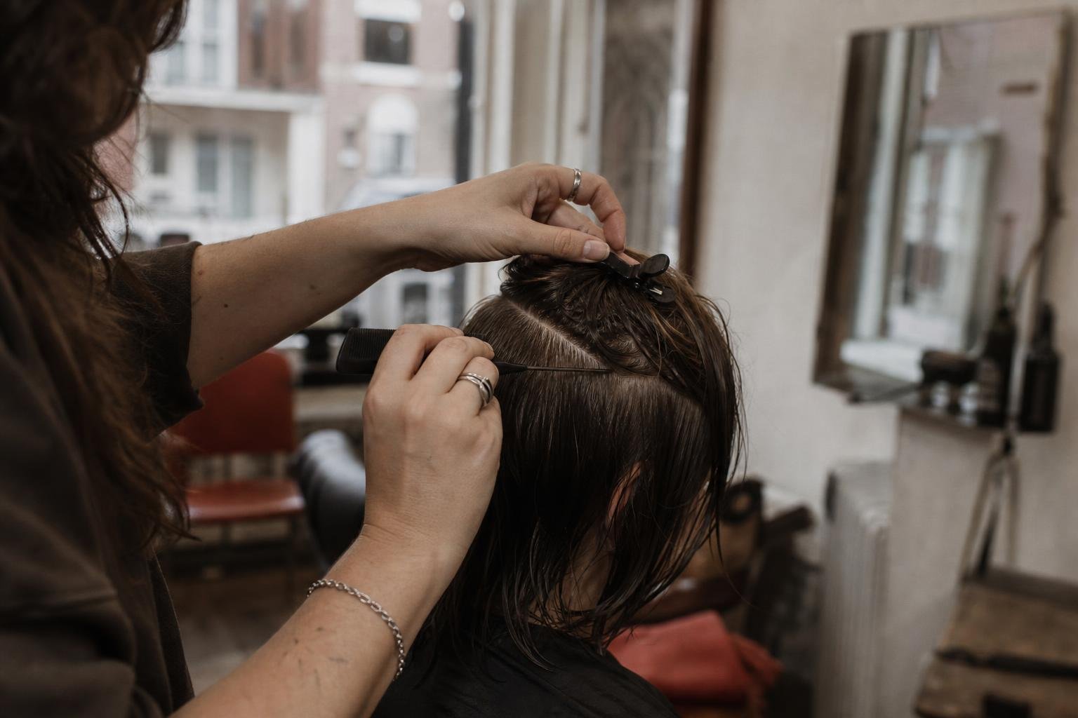 A stylist's hands sectioning a client's wet hair with a tail comb, the work a salon's own pages should show, not a Fresha listing