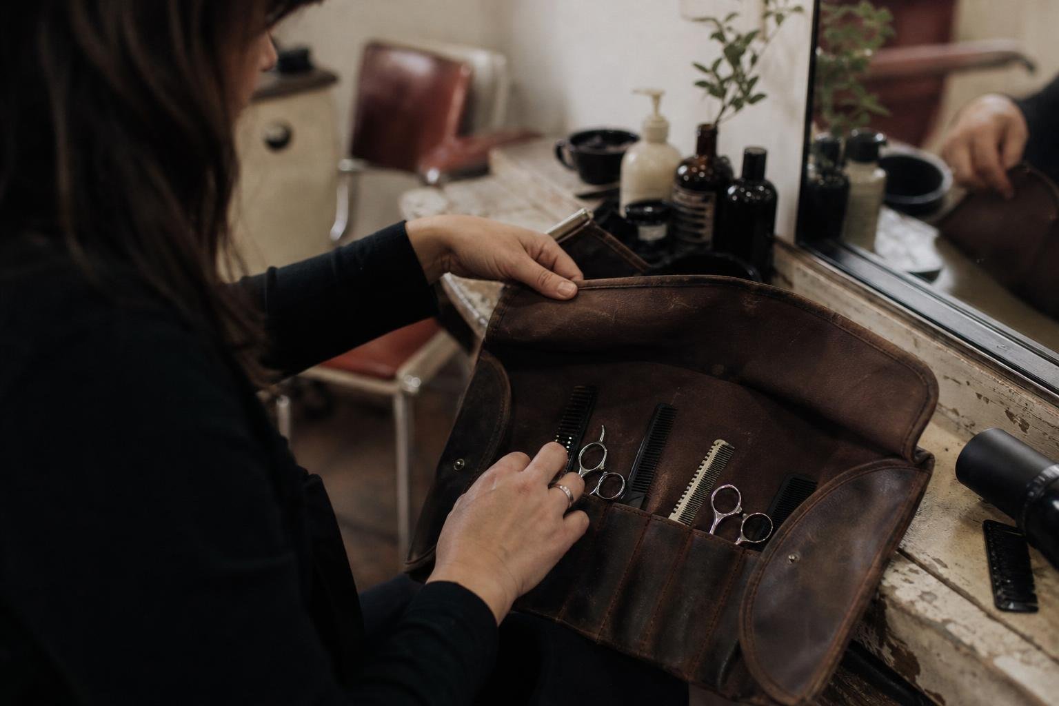 A hairdresser rolling her scissors into her own leather case, kit she owns in a way she never owns a booking app website